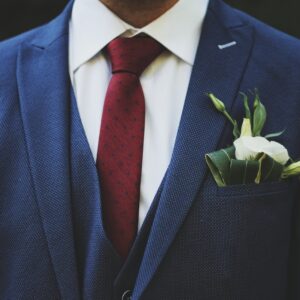 person wearing blue suit jacket and red necktie