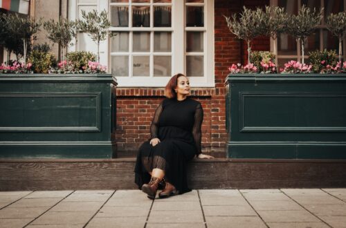 woman in black long sleeve shirt sitting on sidewalk during daytime