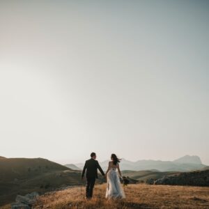 a bride and groom walking on a hill