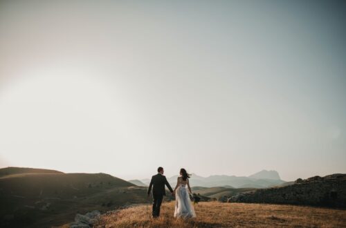 a bride and groom walking on a hill