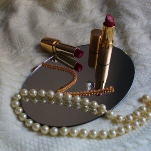 white pearl necklace beside pink lipstick