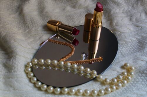 white pearl necklace beside pink lipstick