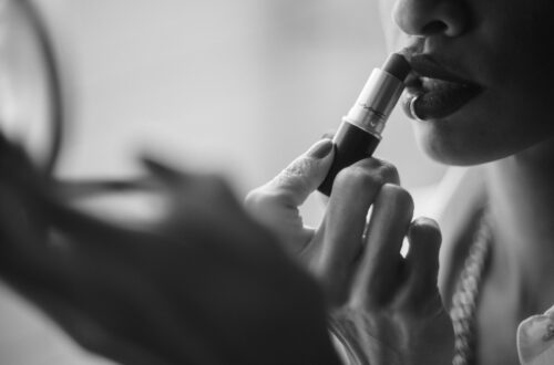 grayscale photo of woman putting lipstick on her lips