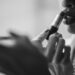 grayscale photo of woman putting lipstick on her lips